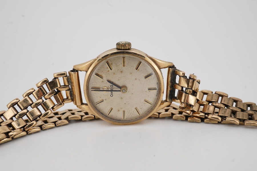 A lady's 9ct gold Omega manual wind wrist watch, with baton numerals, case diameter 20mm, on an associated 9ct gold bracelet. Gross weight 21.2 grams. Condition - poor to fair.